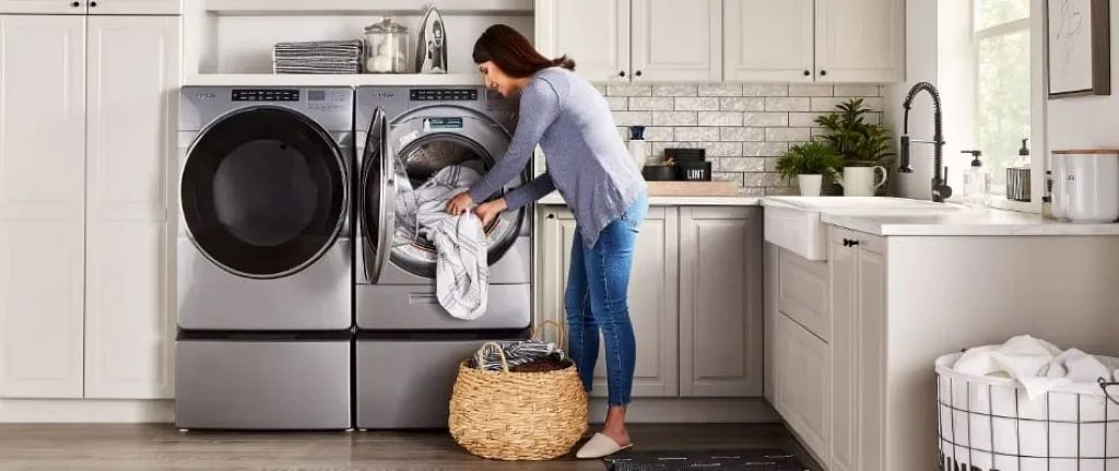 Front-loading washing machine with a level tool placed on top, showing proper leveling for stability and longer appliance life