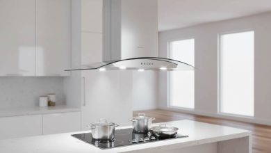 Sleek stainless steel 30-inch island range hood hanging over a modern kitchen cooktop with LED lights illuminating the surface