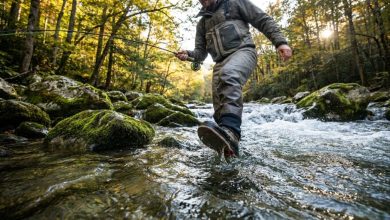 An angler wearing specialized wading boots while standing on slippery river rocks.