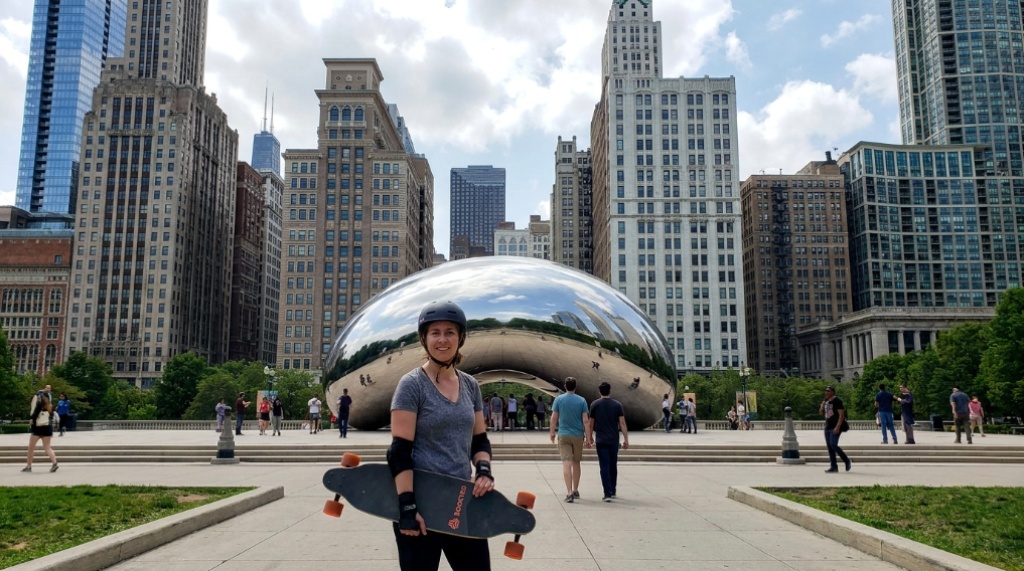 Beginner holding a colorful skateboard in an Illinois park.