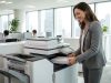 Business professional analyzing printer supply invoices and paper stacks at a desk.